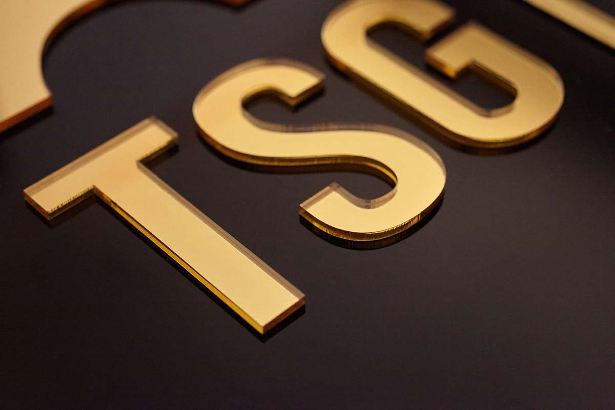 Detalle de letrero de acrilico negro y espejo oro gold